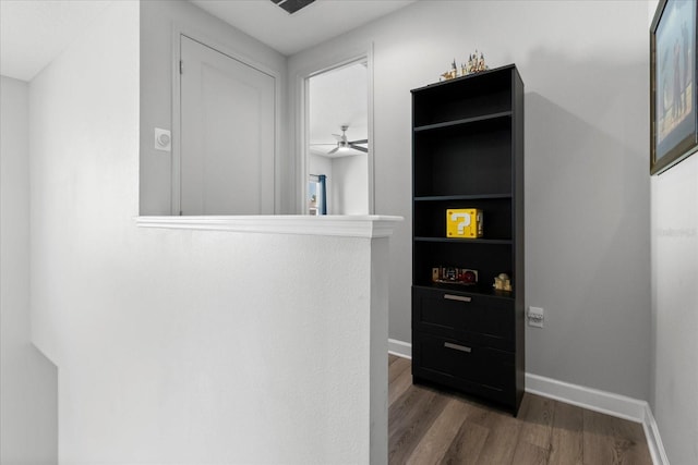 corridor featuring baseboards and wood finished floors