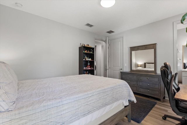 bedroom with light wood-style floors and visible vents