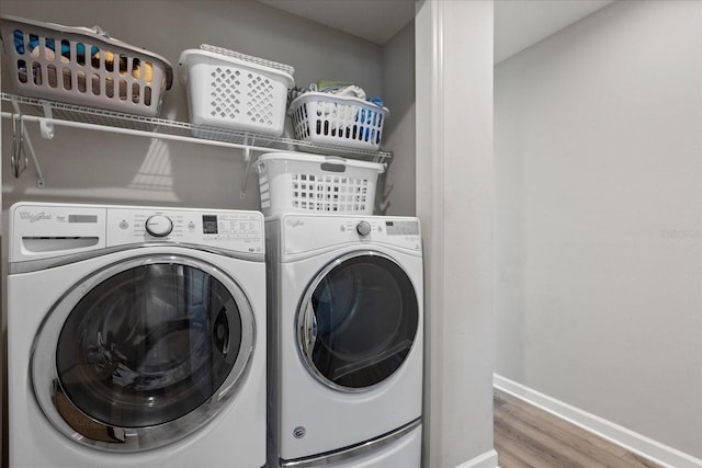 laundry room with washing machine and dryer, baseboards, wood finished floors, and laundry area