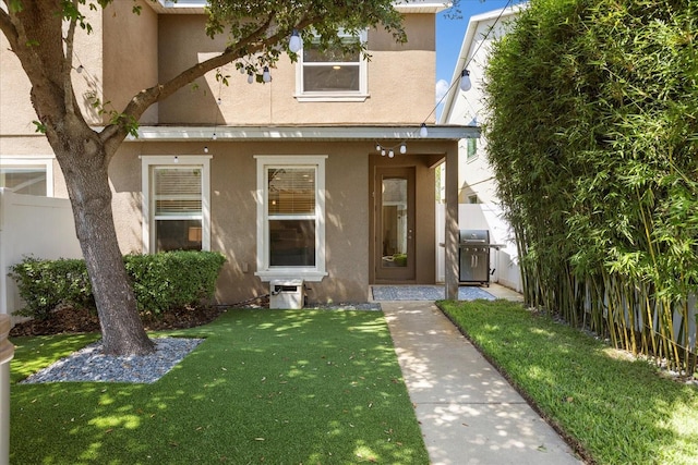 view of front of property with a front lawn, stucco siding, and fence