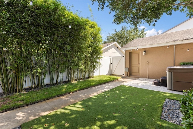 view of yard with a gate, fence, a hot tub, and a patio area