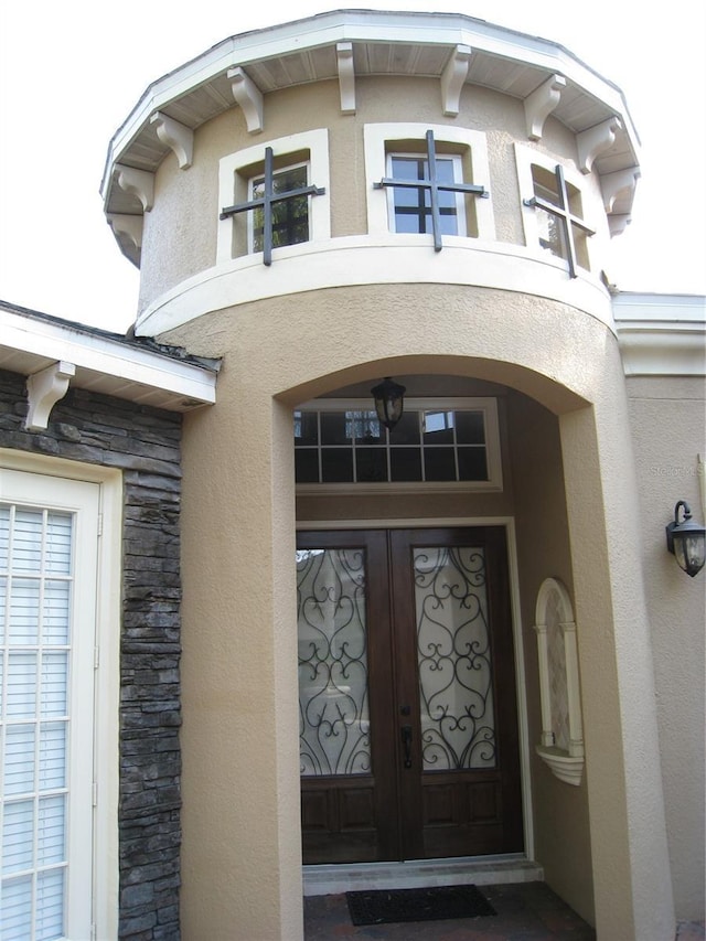 view of exterior entry featuring stucco siding, french doors, and stone siding