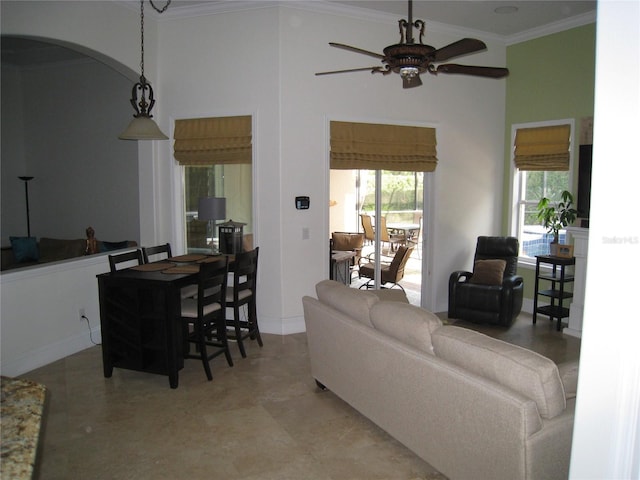 living room featuring a high ceiling, crown molding, baseboards, ceiling fan, and arched walkways
