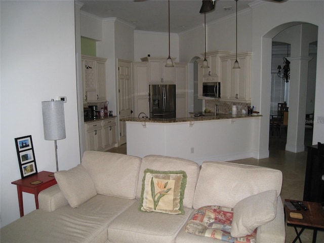 living room with crown molding, visible vents, and arched walkways