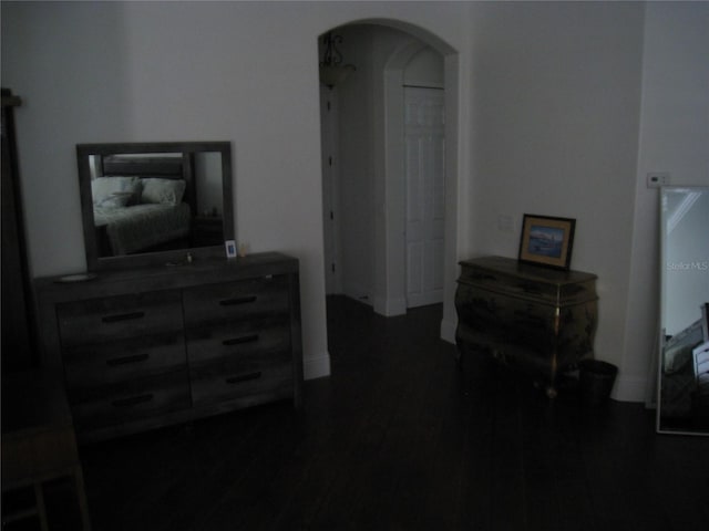 interior space with arched walkways, dark wood-type flooring, and baseboards