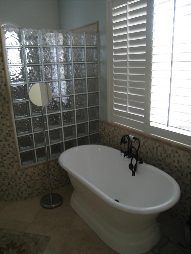 full bath with a soaking tub, tile walls, and tile patterned flooring