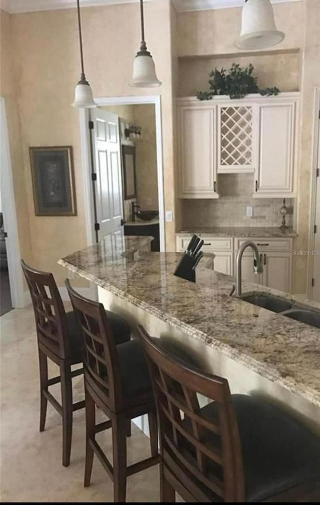kitchen with a sink, ornamental molding, and decorative light fixtures