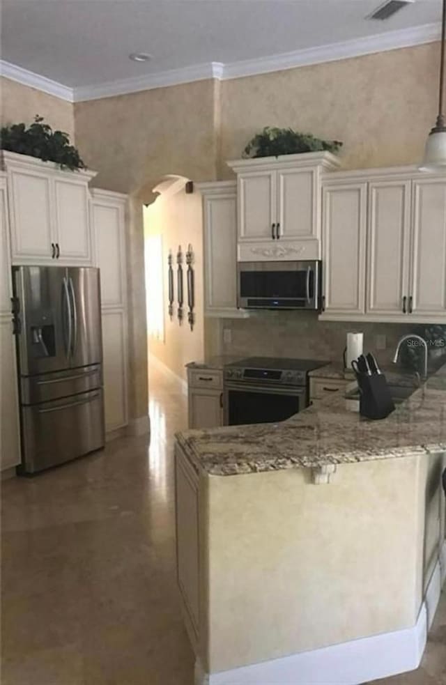 kitchen with a peninsula, stainless steel appliances, light stone countertops, arched walkways, and ornamental molding
