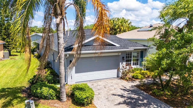 151 Bell Tower Xing W, Kissimmee, FL 34759 - view of front of home with a front yard, an attached garage, roof with shingles, decorative driveway, and central AC