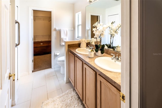 151 Bell Tower Xing W, Kissimmee, FL 34759 - bathroom featuring double vanity, toilet, a spacious closet, and tile patterned flooring