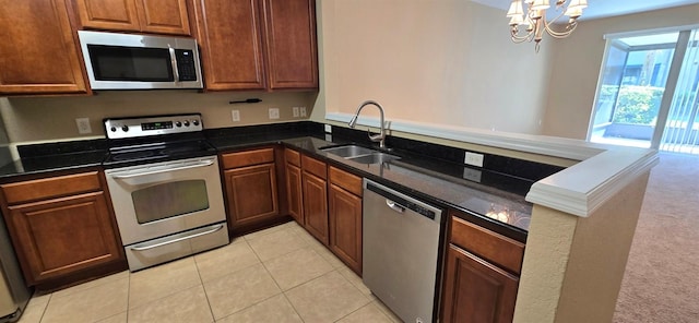 kitchen with a peninsula, stainless steel appliances, a sink, an inviting chandelier, and light tile patterned floors