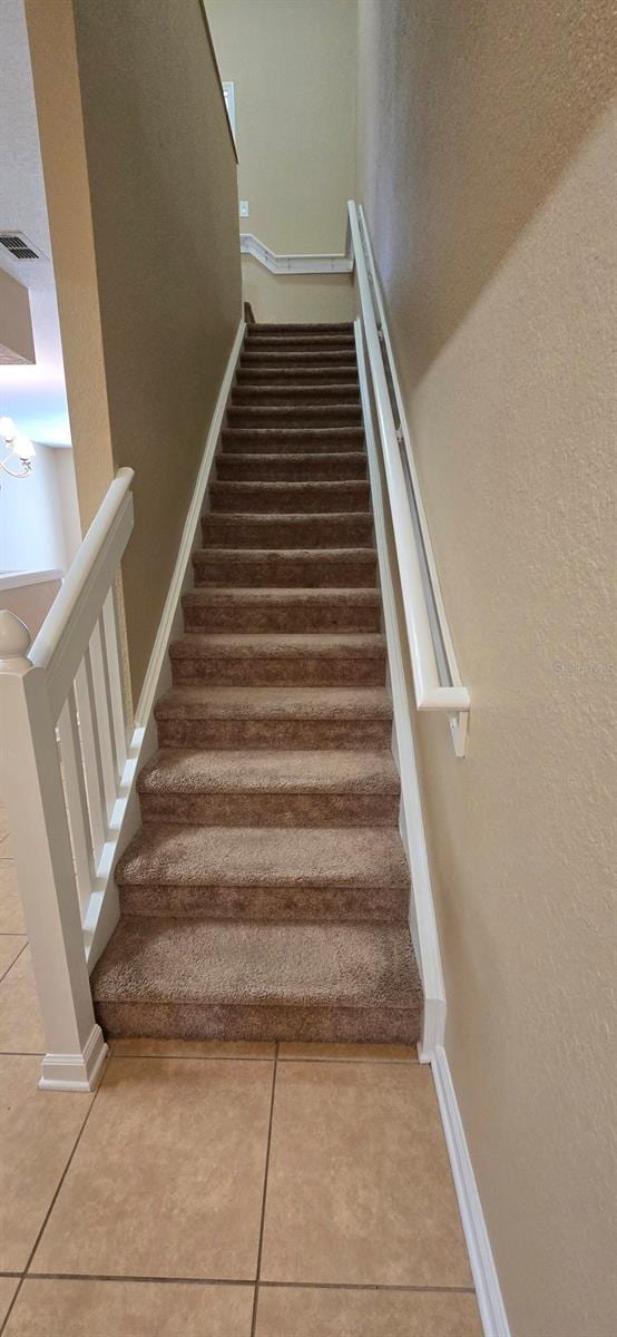 staircase featuring baseboards, visible vents, and tile patterned floors