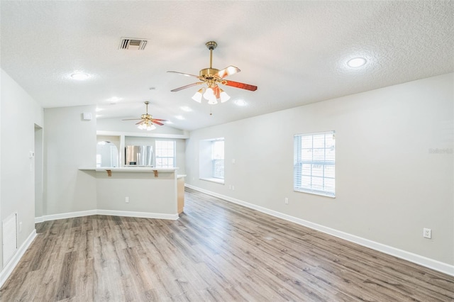 unfurnished living room with visible vents, ceiling fan, wood finished floors, and a textured ceiling