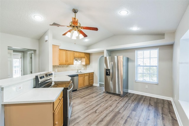 kitchen with light wood-style flooring, light countertops, a ceiling fan, lofted ceiling, and appliances with stainless steel finishes