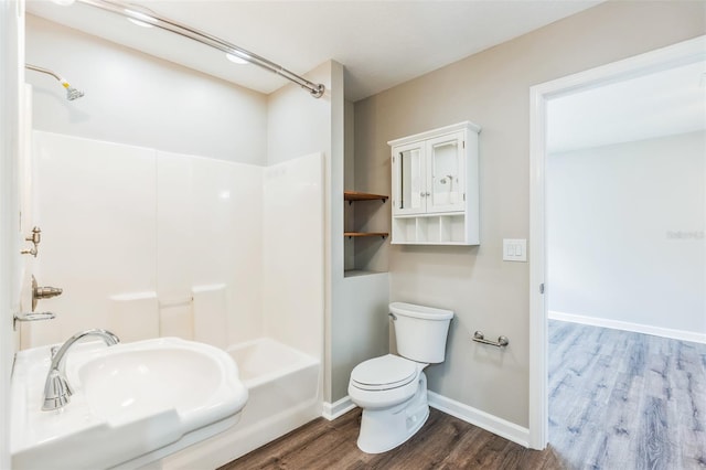 bathroom featuring a shower, wood finished floors, a sink, and toilet