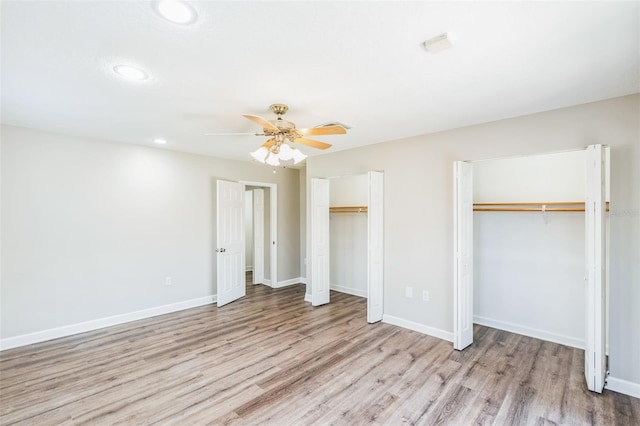 unfurnished bedroom featuring wood finished floors, recessed lighting, baseboards, and multiple closets