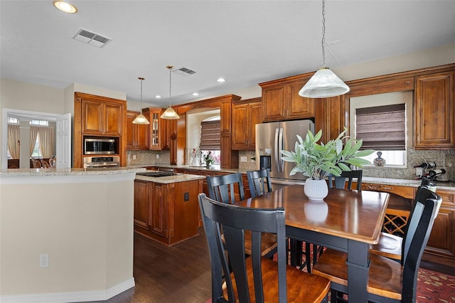 3033 Zaharias Dr, Orlando, FL 32837 - kitchen with visible vents, dark wood finished floors, brown cabinets, stainless steel appliances, and a kitchen island