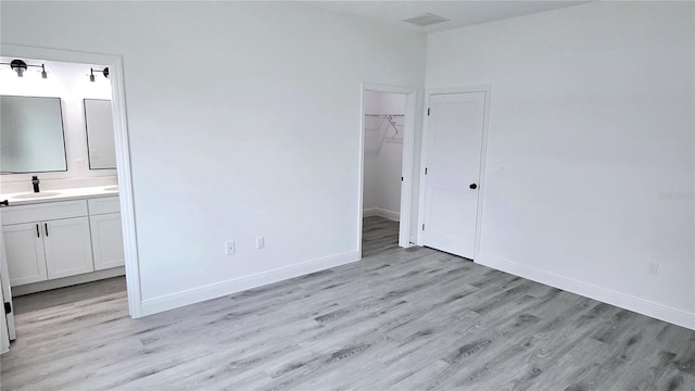 699 Marion Oaks Trl, Ocala, FL 34473 - unfurnished bedroom featuring light wood-style floors, a sink, baseboards, and a spacious closet