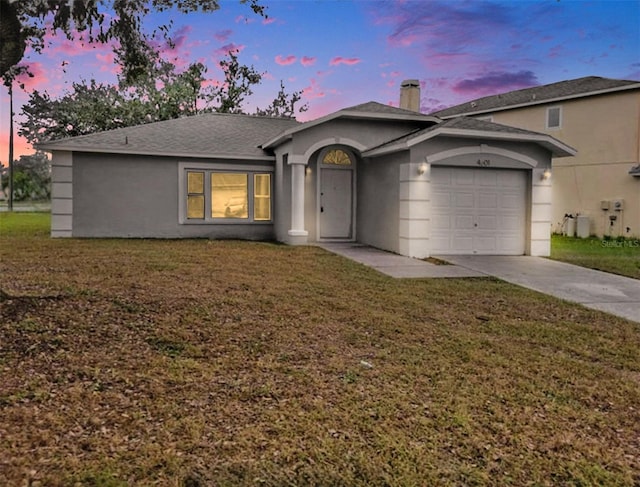 ranch-style home with stucco siding, a yard, an attached garage, and concrete driveway
