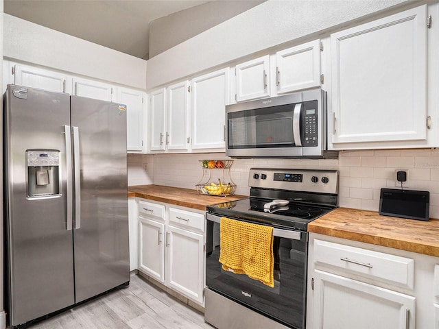 kitchen with white cabinets, decorative backsplash, appliances with stainless steel finishes, and butcher block counters