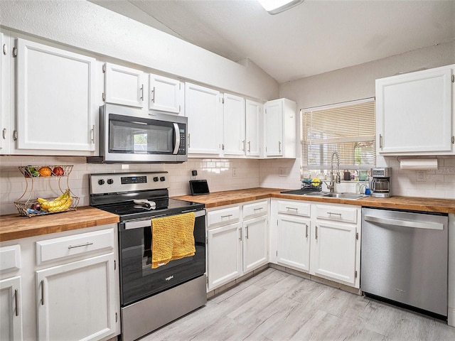 kitchen with wood counters, a sink, white cabinetry, and appliances with stainless steel finishes