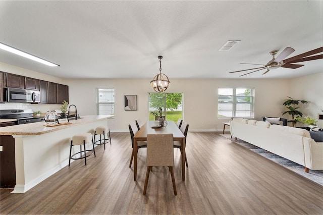 dining area with visible vents, baseboards, ceiling fan with notable chandelier, and wood finished floors