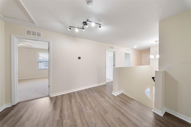 empty room featuring visible vents, baseboards, attic access, and wood finished floors
