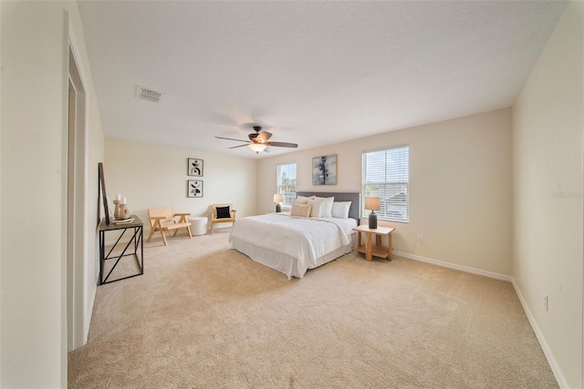 bedroom with light carpet, visible vents, baseboards, and a ceiling fan