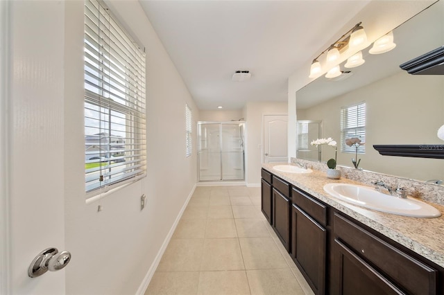 bathroom featuring a shower stall, a sink, tile patterned floors, double vanity, and baseboards
