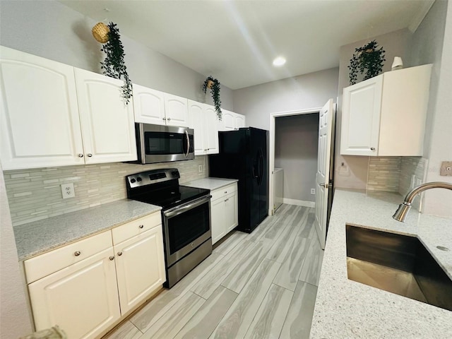 kitchen featuring white cabinets, tasteful backsplash, a sink, and appliances with stainless steel finishes