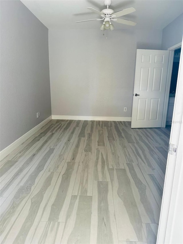 unfurnished room with ceiling fan, wood finished floors, and baseboards