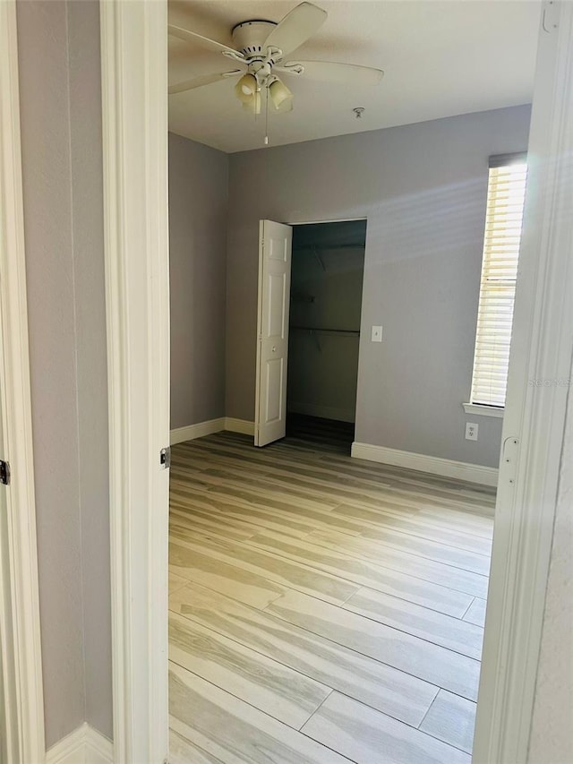 spare room featuring baseboards, a ceiling fan, and light wood-style floors