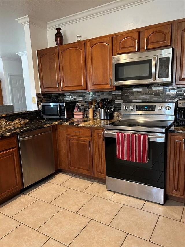 5406 Crepe Myrtle Cir, Kissimmee, FL 34758 - kitchen with brown cabinetry, tasteful backsplash, dark stone countertops, ornamental molding, and stainless steel appliances