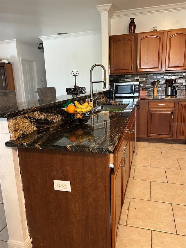 5406 Crepe Myrtle Cir, Kissimmee, FL 34758 - kitchen with light tile patterned flooring, stainless steel microwave, ornamental molding, and tasteful backsplash
