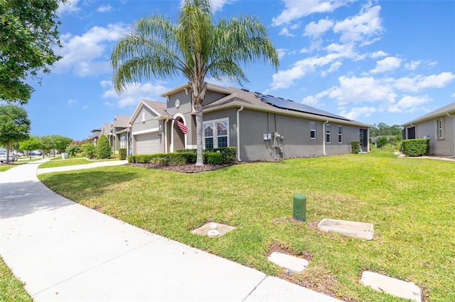 view of front of house featuring a garage, a front lawn, roof mounted solar panels, and stucco siding
