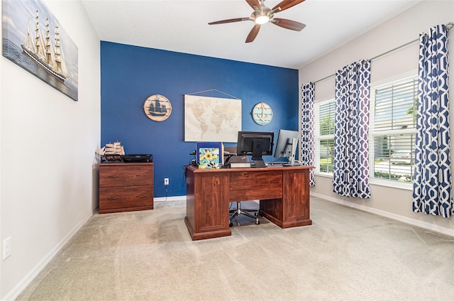 carpeted office space featuring baseboards and ceiling fan