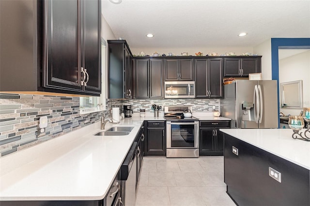 kitchen with backsplash, stainless steel appliances, light countertops, and a sink