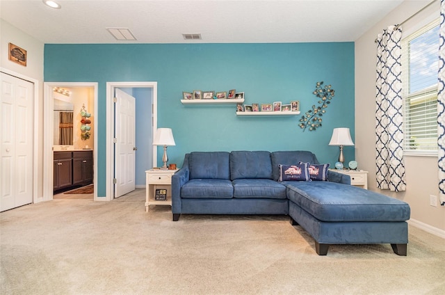 living area featuring light colored carpet, baseboards, and visible vents
