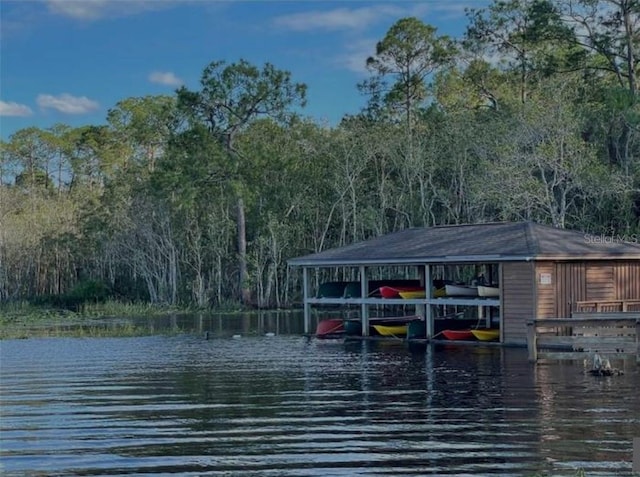 view of dock featuring a forest view, boat lift, and a water view