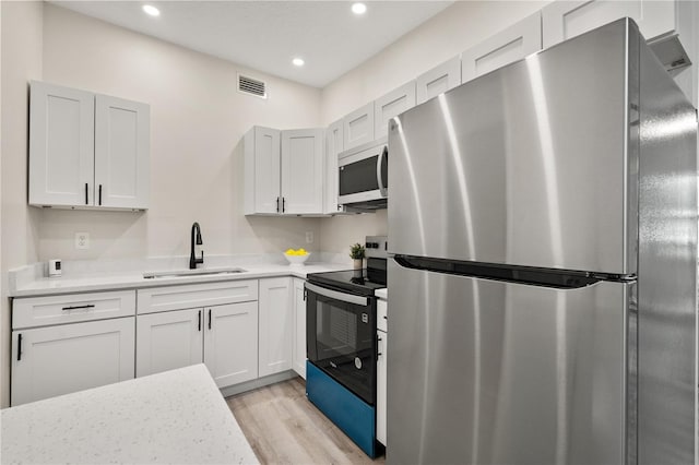 101 W Wallace St, Orlando, FL 32809 - kitchen with light countertops, a sink, appliances with stainless steel finishes, light wood-style flooring, and visible vents