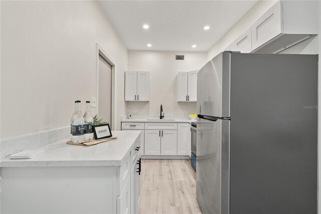 101 W Wallace St, Orlando, FL 32809 - kitchen with white cabinets, visible vents, a sink, light wood-style floors, and freestanding refrigerator