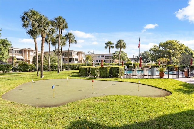 view of property's community featuring fence, a swimming pool, and a lawn
