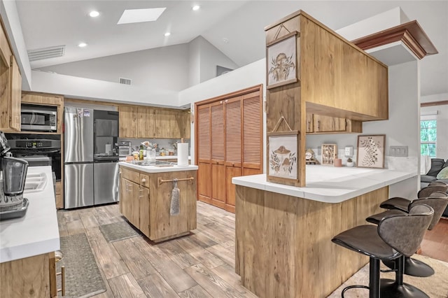 2475 Cox Rd, Cocoa, FL 32926 - kitchen featuring lofted ceiling with skylight, stainless steel appliances, light wood-style flooring, a peninsula, and visible vents