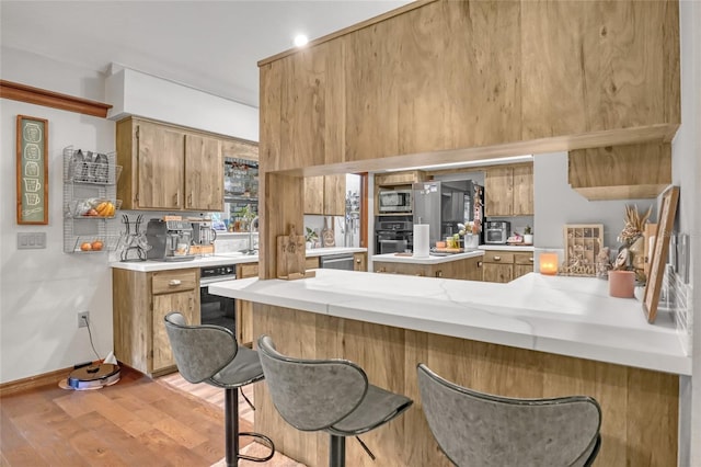 2475 Cox Rd, Cocoa, FL 32926 - kitchen with brown cabinets, light wood finished floors, light countertops, a peninsula, and appliances with stainless steel finishes