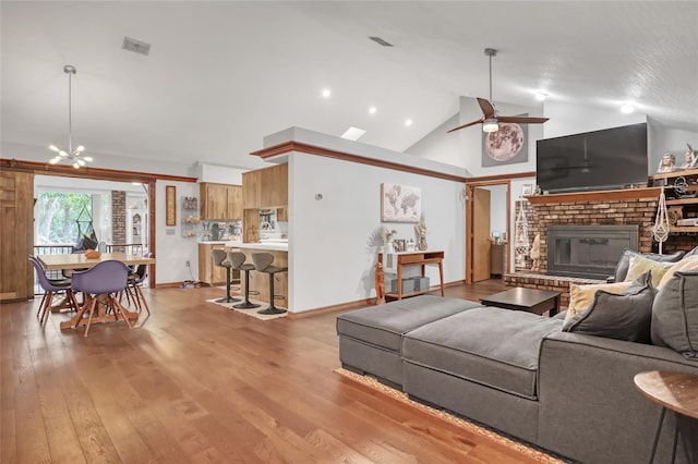 2475 Cox Rd, Cocoa, FL 32926 - living area with a fireplace, light wood-style floors, visible vents, and ceiling fan with notable chandelier