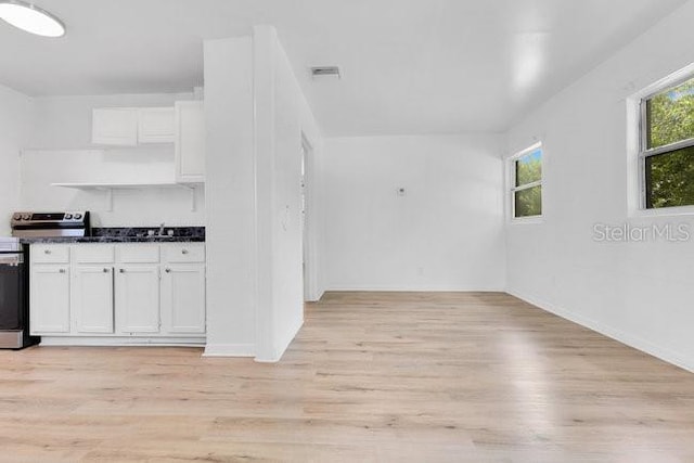 spare room featuring light wood finished floors, baseboards, and a sink