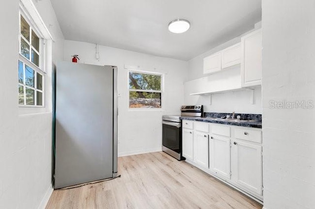 kitchen featuring stainless steel appliances, white cabinets, dark countertops, and light wood-style floors