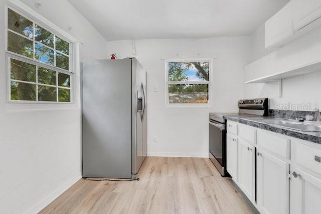 kitchen featuring appliances with stainless steel finishes, light wood finished floors, dark countertops, and white cabinetry