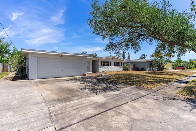 ranch-style house featuring concrete driveway, an attached garage, a front yard, and stucco siding