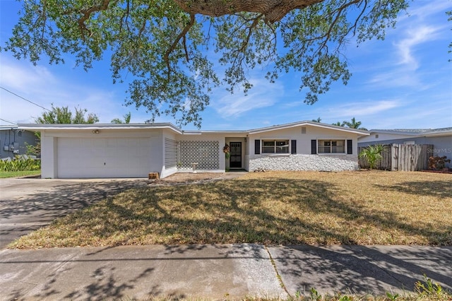 ranch-style home with fence, an attached garage, driveway, and a front yard